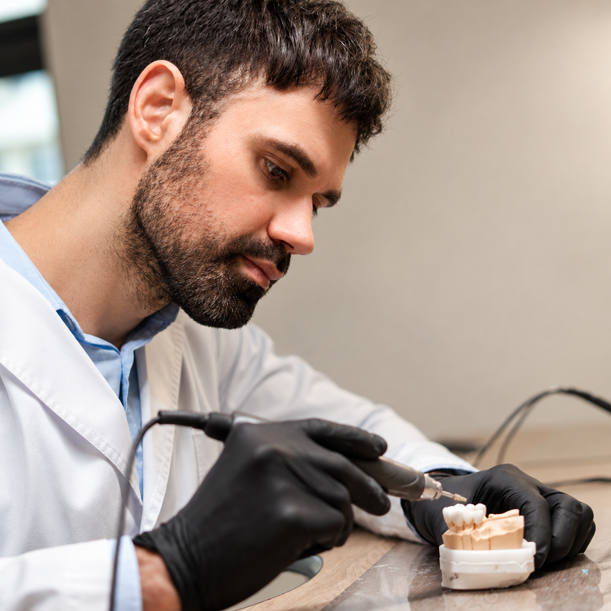Dental technician shaping a restoration on a model